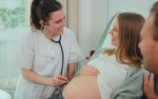 Feliz mujer embarazada que visita a la matrona en la clínica de maternidad